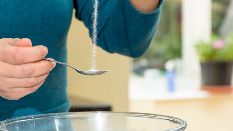 Person adding salt to bowl
