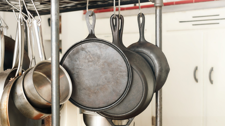Pots and pans hanging from a kitchen rack, including old cast iron
