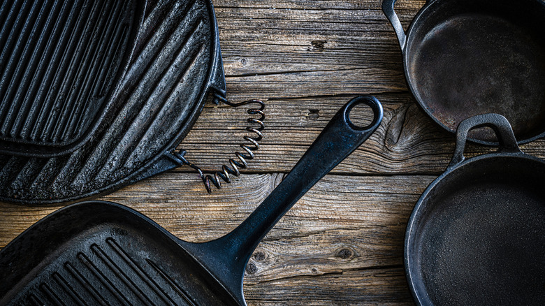 Assorted vintage cast iron pans on a wooden table