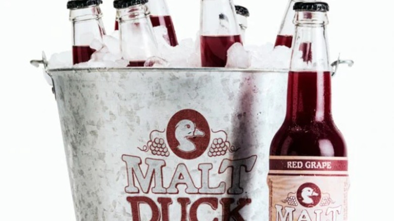 a bottle of malt duck next to an pail full of ice and malt ducks