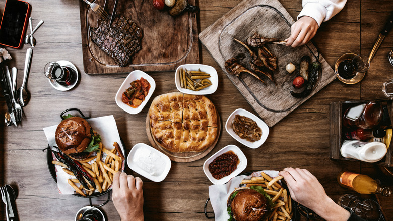Top view of beef steaks, burgers and snacks with grilled vegetables on table.