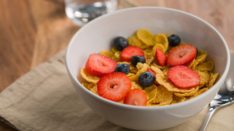 A bowl of Special K-like cereal topped with fresh blueberries and strawberry slices
