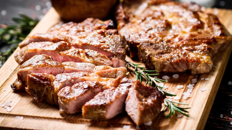 sliced pork chops with rosemary on wooden board