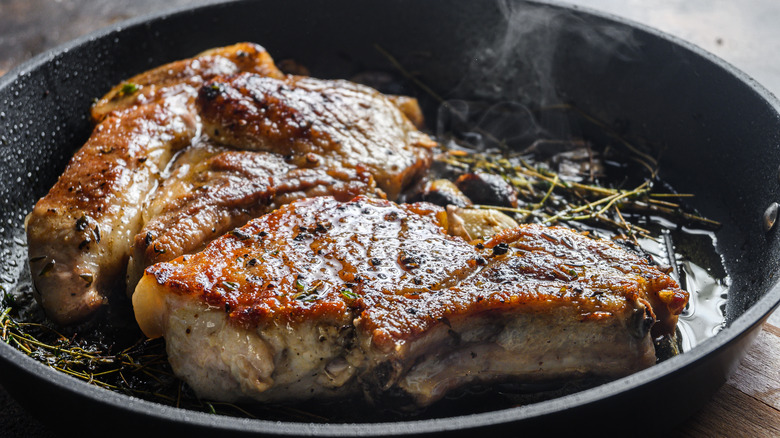 pork chops searing in frying pan