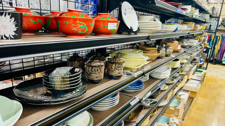 Several shelves of dishware at a thrift store