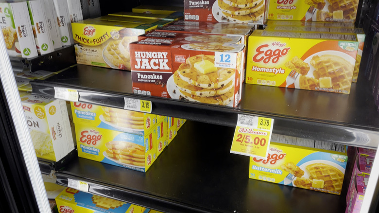 An assortment of frozen waffles and pancakes in a grocery store freezer aisle
