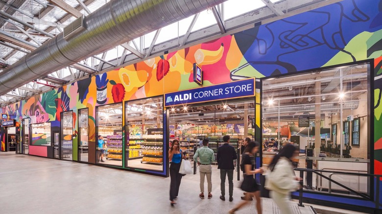 Exterior view of an Aldi Corner Store, with a bright, abstract mural of groceries covering the whole front