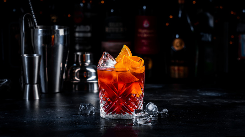 A Negroni cocktail and ice on a bar
