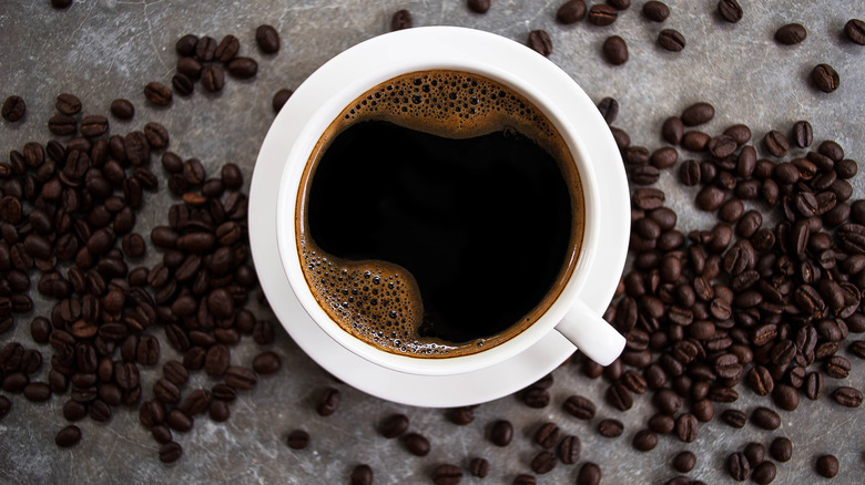 overhead view of a cup of coffee and coffee beans