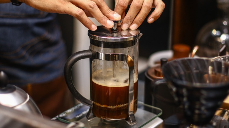hands pushing french press plunger 