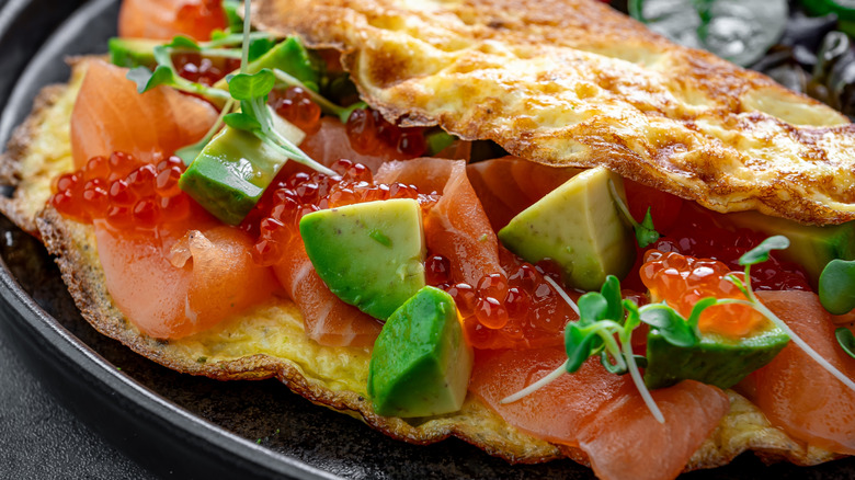 Closeup of an omelet stuffed with smoked salmon, salmon roe, avocado, and herbs