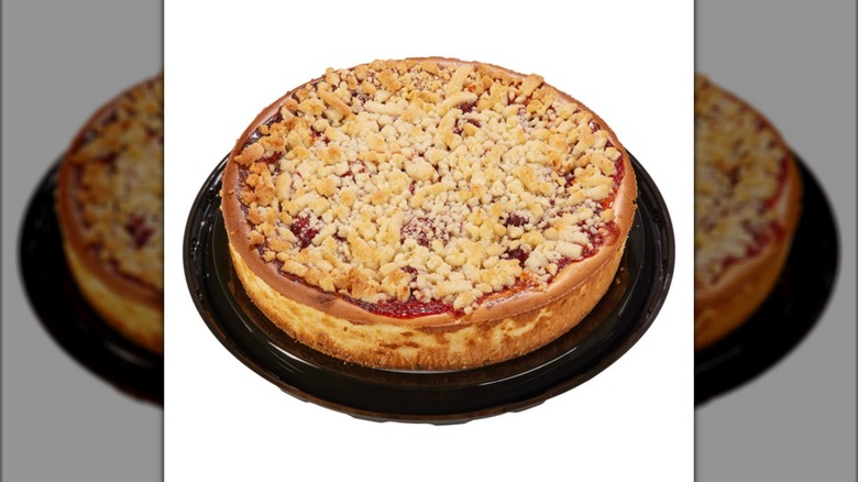 A whole cheesecake topped with a strawberry sauce and lots of streusel