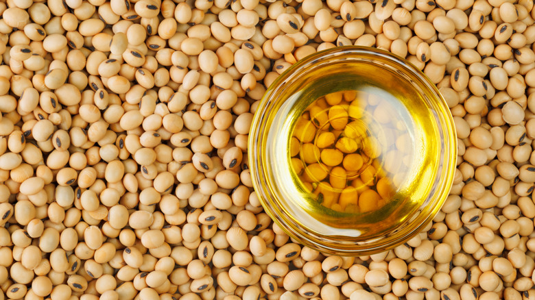 A bowl of soybean oil on a pile of soybeans