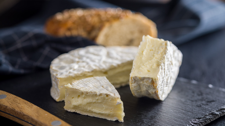 Cut wheel of brie cheese on a black stone surface
