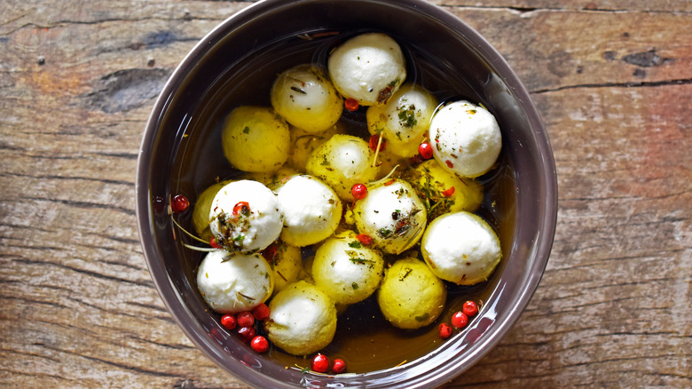Balls of marinated goat cheese in a brown bowl