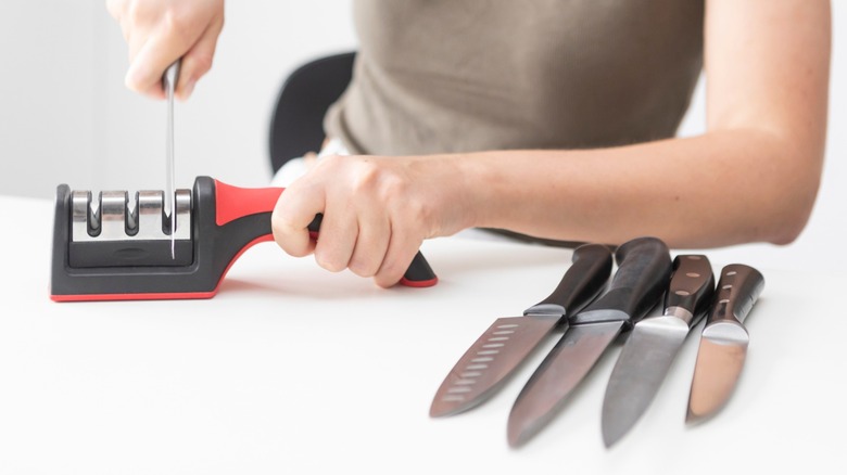 Person using a pull-through sharpener on kitchen knives