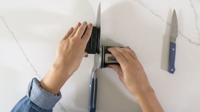 Person using roller sharpener on kitchen knives