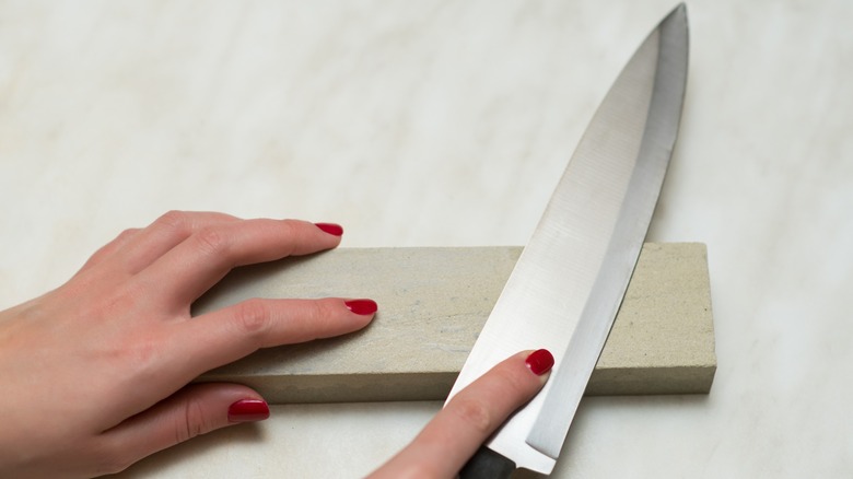 Person using a whetstone to sharpen a chef's knife