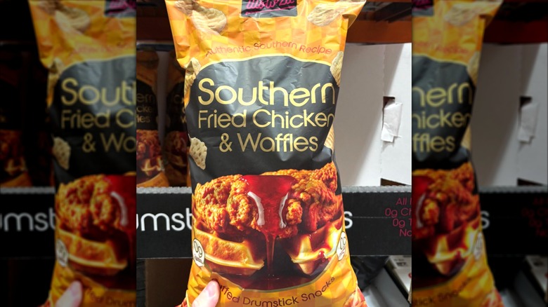 A hand holding a bag of Wowza Southern Fried Chicken & Waffles chips in a Costco aisle
