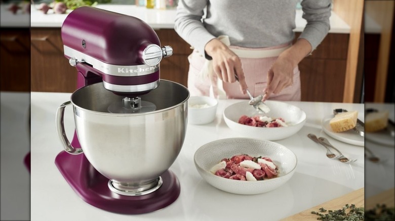 Woman in the kitchen cooking with a beetroot-colored KitchenAid stand mixer