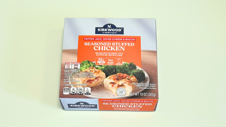 A box of Kirkwood Pepper Jack, Swiss Cheese, and Bacon Seasoned Stuffed Chicken isolated on a light green background
