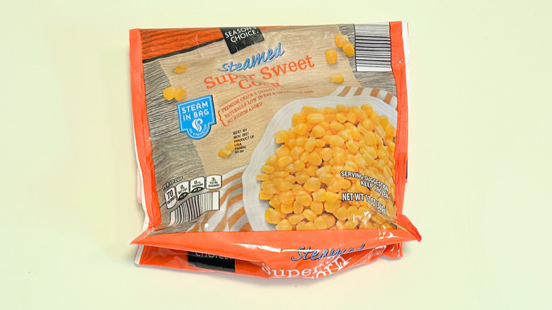 A bag of Season's Choice Steamed Super Sweet Corn isolated on a light green background
