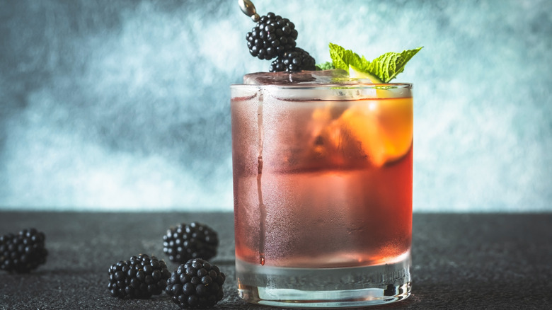 drink in rocks glass with mint sprig and skewered blackberries