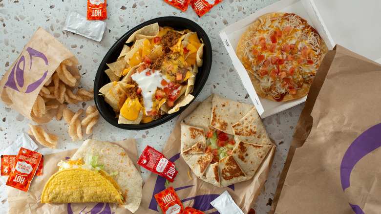 Table with assorted Taco Bell food including cinnamon twists, nachos, Mexican pizza, taco, and crunchwrap