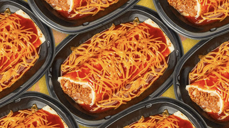 Enchiritos in black plastic containers covered in red sauce and shredded orange cheese