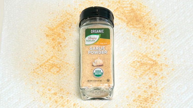 A bottle of Simply Nature Organic Garlic Powder next to garlic powder on a white background