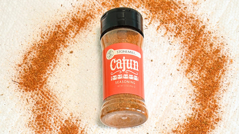A bottle of Stonemill Cajun Seasoning next to Cajun seasoning on a white background