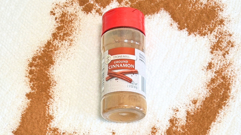 A bottle of Stonemill Ground Cinnamon next to ground cinnamon on a white background