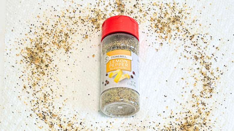A bottle of Stonemill Lemon Pepper Seasoning next to lemon pepper on a white background