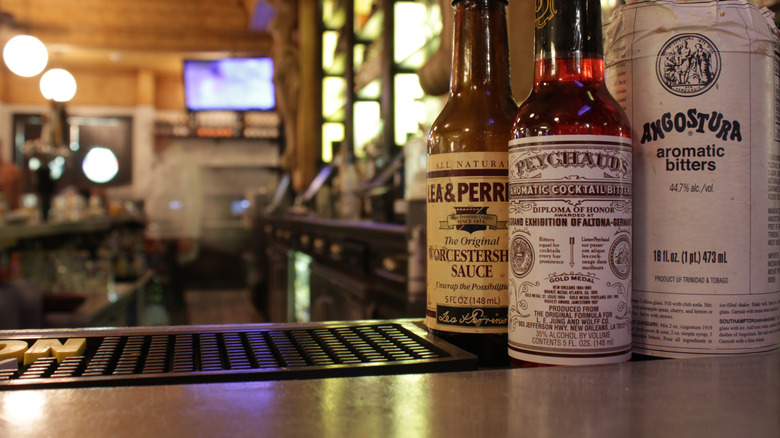 View looking into a bar from the counter, with Peychaud's bitters featured prominently between Worcestershire sauce and Angostura bitters