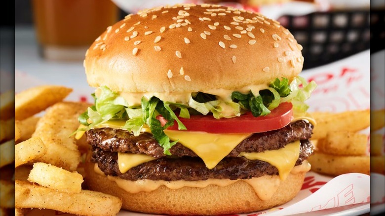 a double cheeseburger with tomato and lettuce and a side of fries