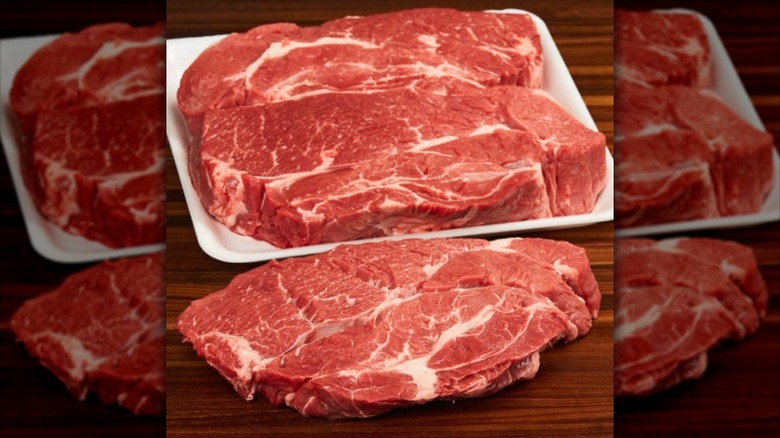 Slabs of raw beef chuck roast on a wooden table