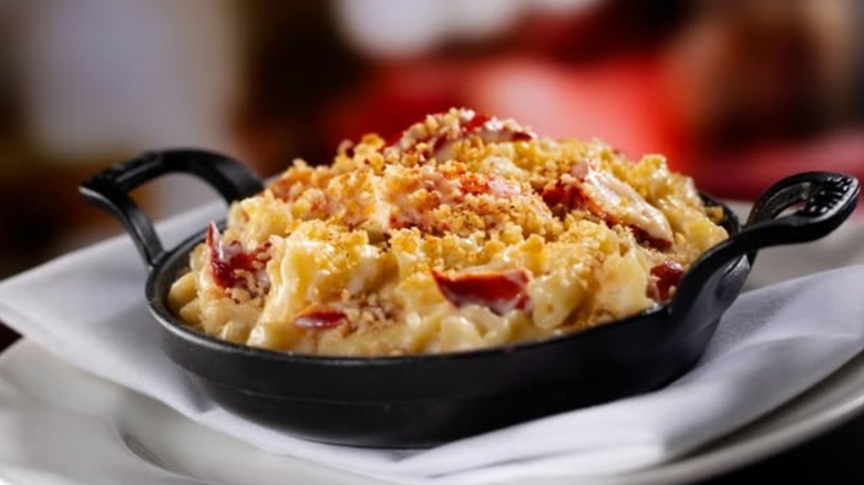 A small cast iron serving dish with mac and cheese and lobster chunks
