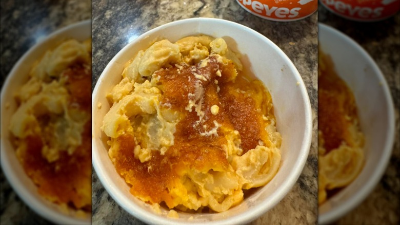 A cup of Popeye's mac and cheese on a granite countertop
