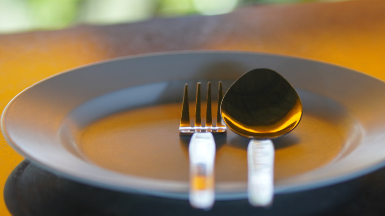 A spoon and fork on a plate, on a restaurant table