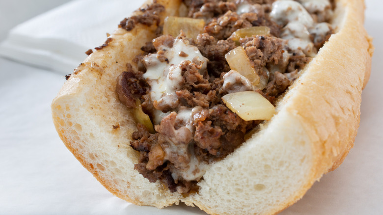 A Philly cheesesteak on a thick roll with shaved beef, sauteed onions and melted cheese on top