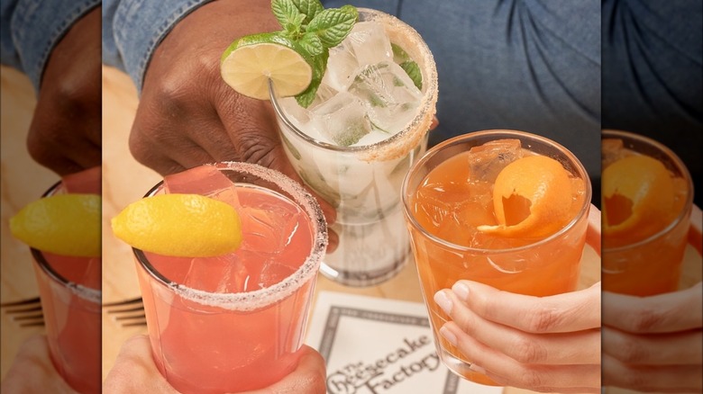 Three hands holding cocktails