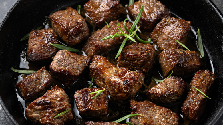 Steak bites in a cast-iron skillet with herbs