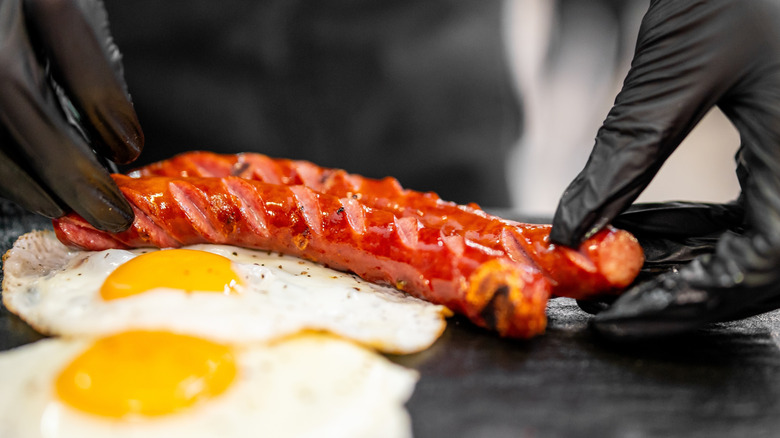 A person arranging juicy grilled spiral sausages