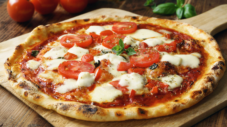 Pizza topped with tomato slices and blocks of cheese