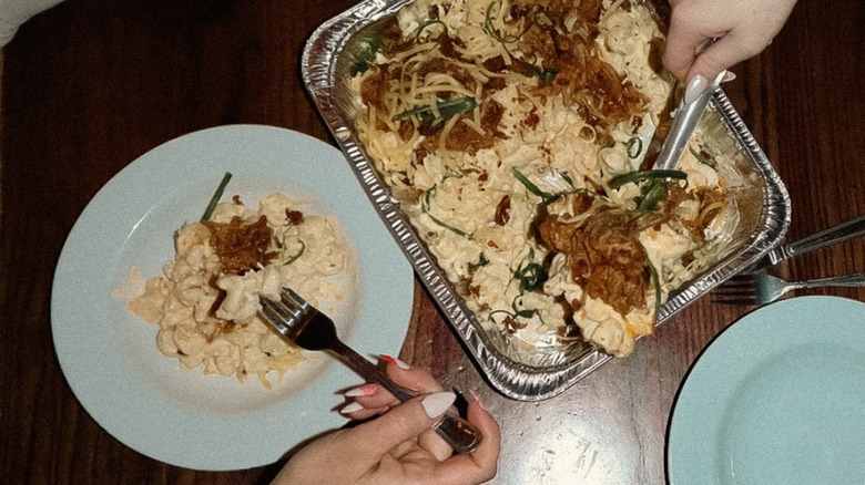 Overhead view of hands serving Leadbelly mac and cheese from tray