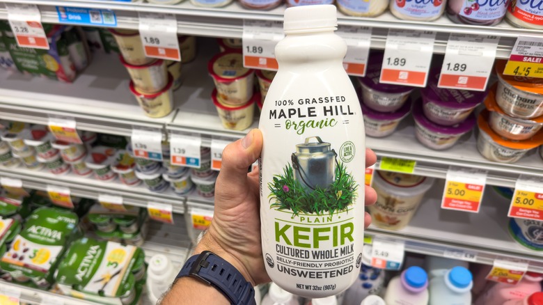A person holding a bottle of Maple Hill Organic Keifir at a grocery store