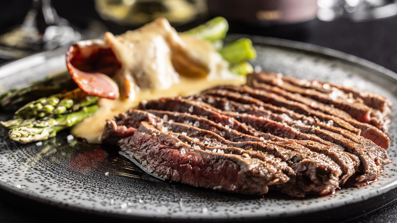 Sliced steak on a plate seasoned with flaked sea salt.