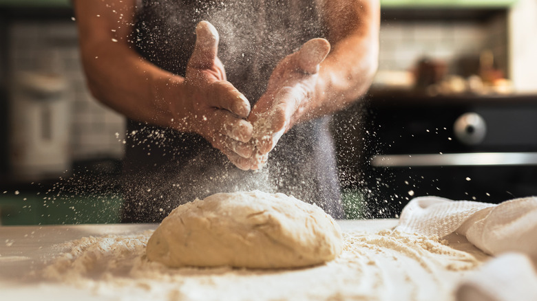 Man flouring bread dough on counter