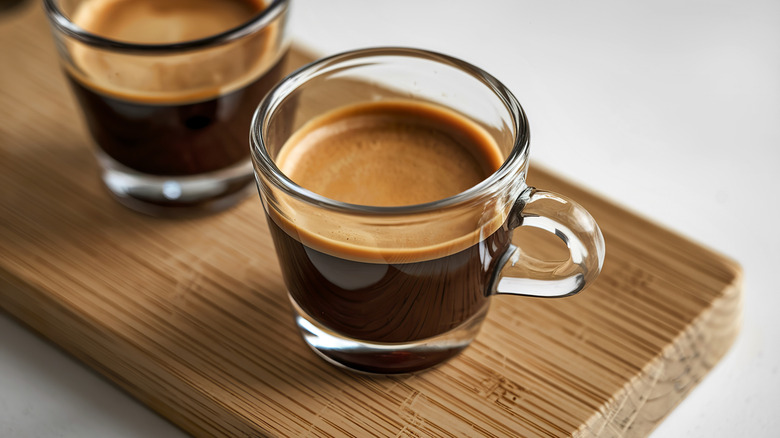 espresso shots in clear glasses ready to drink on a wooden board