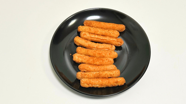 A black plate of chicken fries on a white surface